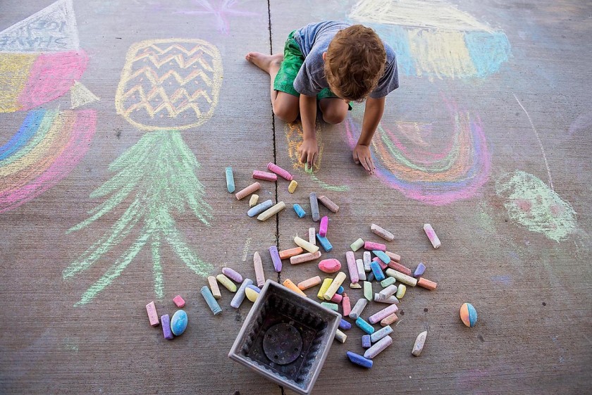 child drawing with sidewalk chalk by Allison Gipson