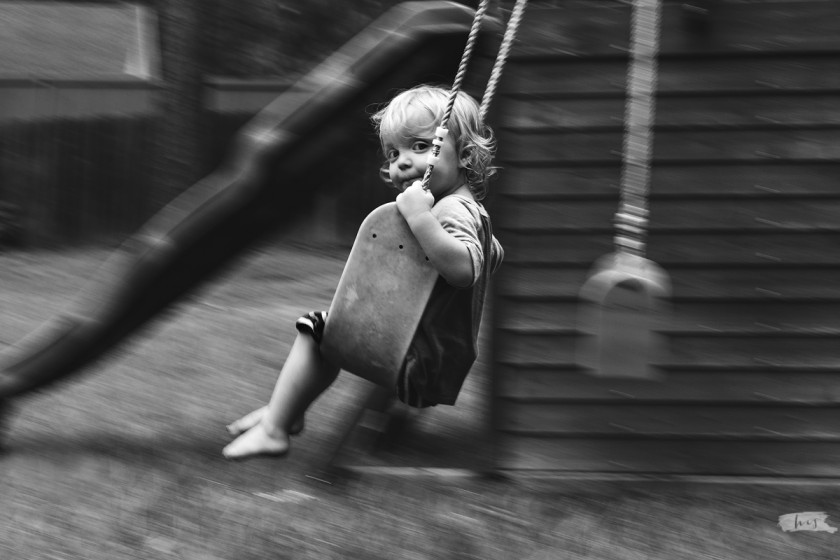 black and white panning photo of boy swinging by Heather Stockett
