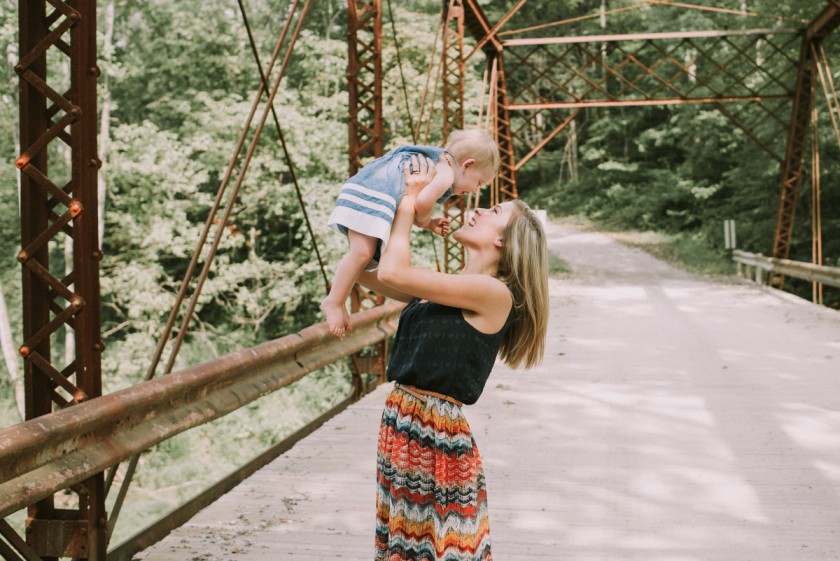 picture of mom holding up baby girl on a bridge by Kaela Elliott