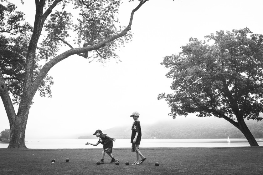 two boys rolling balls in a field by Holly Berfield