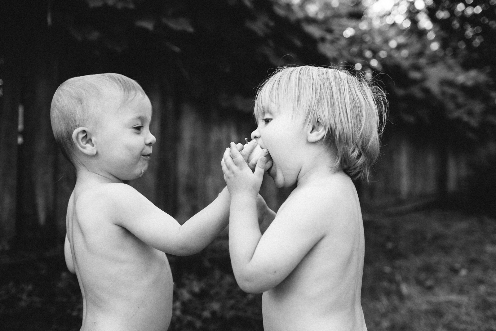 black and white photo of two boys sharing an apple by Meghan McMackin