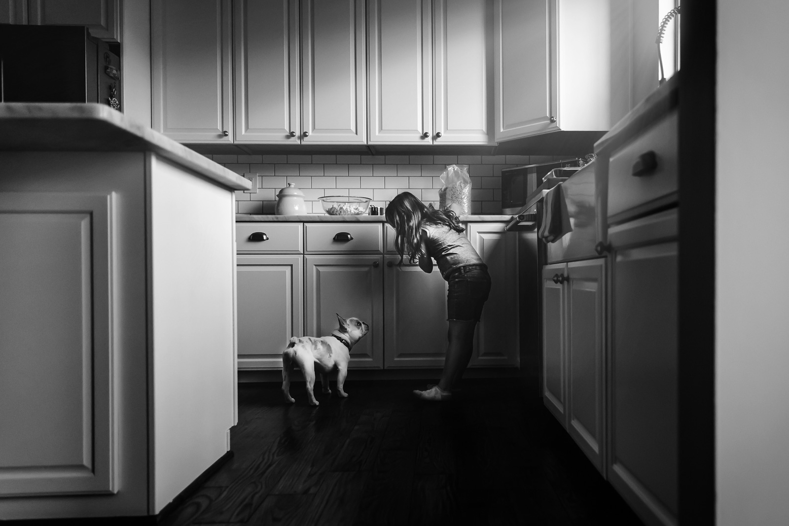 black and white pic of girl and dog in the kitchen by Jennifer Nobriga