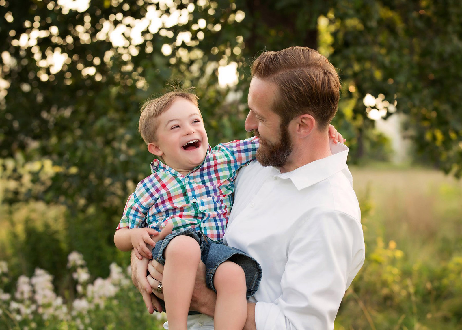 dad holding son in arms smiling and laughing games for happy family photos by leslie crane